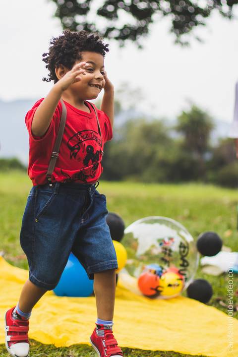 criança de cabelo cacheado correndo na grama brincando '