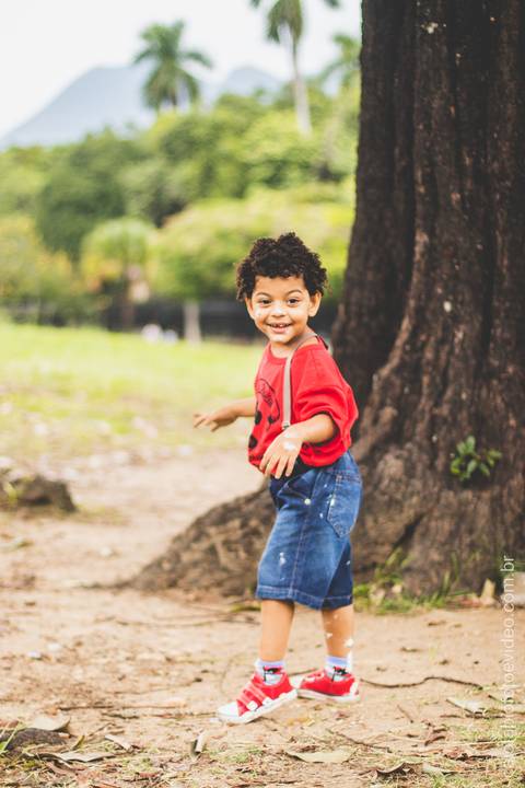 criança pequena posa para foto sentado na árvore'