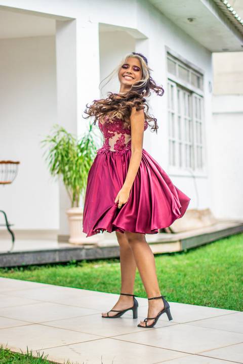 Jovem de vestido vinho dança olhando para câmera'