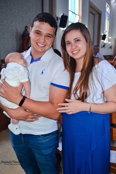 O neném dorme no colo do pai, e a mãe está ao lado.'