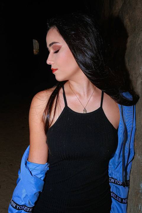 A modelo está encostada em um muro de pedra e olhando para o lado'