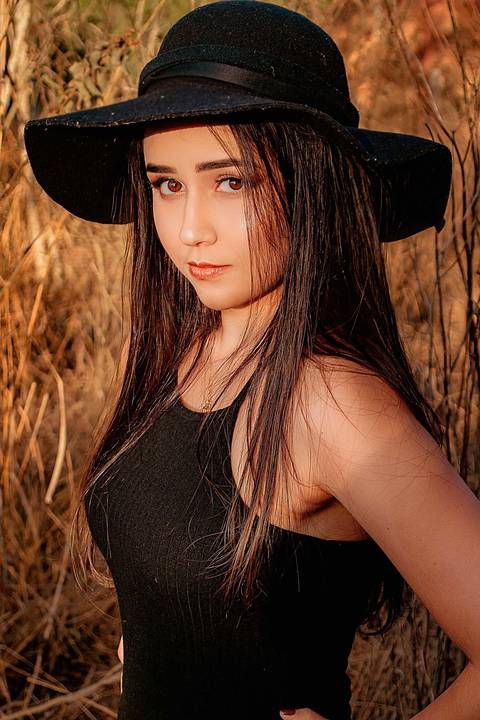 Foto tirada ao por do sol com a modelo de frente e chapéu'