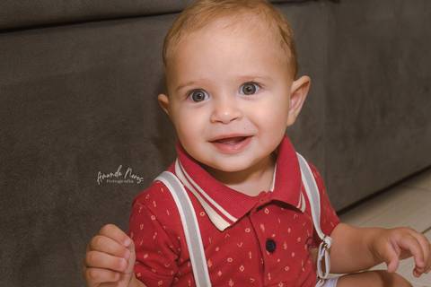 Criança sentada no chão, olhando para câmera e rindo '