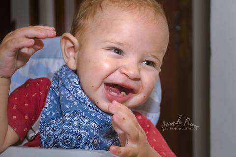 Criança rindo enquanto se alimenta'