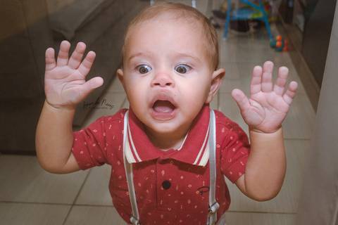 Criança com as mãos e rosto apoiados no vidro da porta '