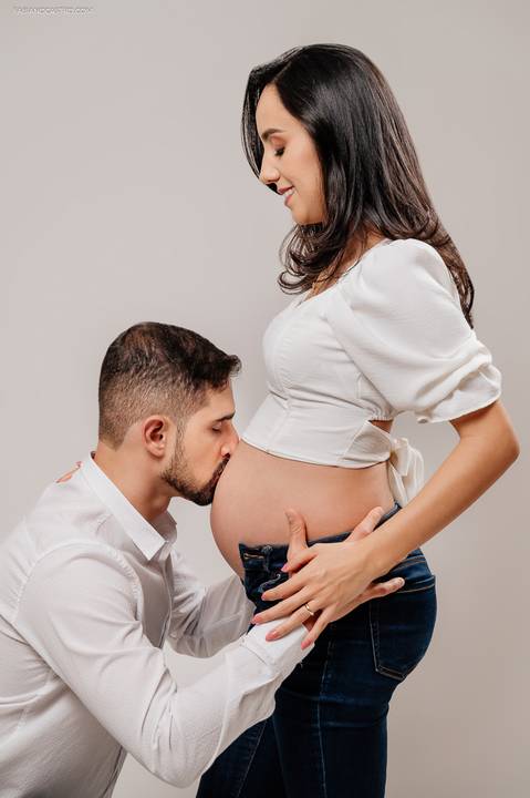 marido beijando a barriga da esposa grávida em estúdio fotográfico'