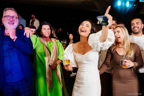 noiva feliz aponta para o noivo no palco durante casamento em fama-mg'