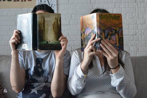 Casal segurando livros em frente ao rosto'