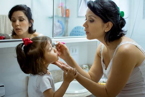 mãe maquiando a filha pequena'