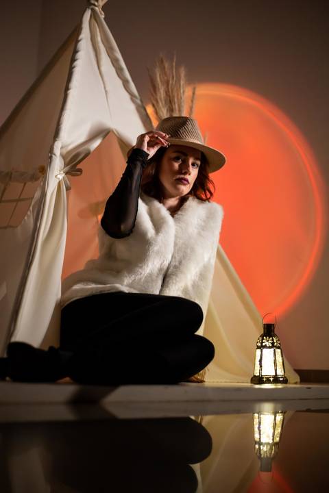 Mulher usando chapéu nos cabelos e vestida com sueter branco.'