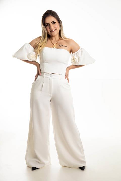 Mulher de cabelos longos loiros vestida de conjunto branco.'