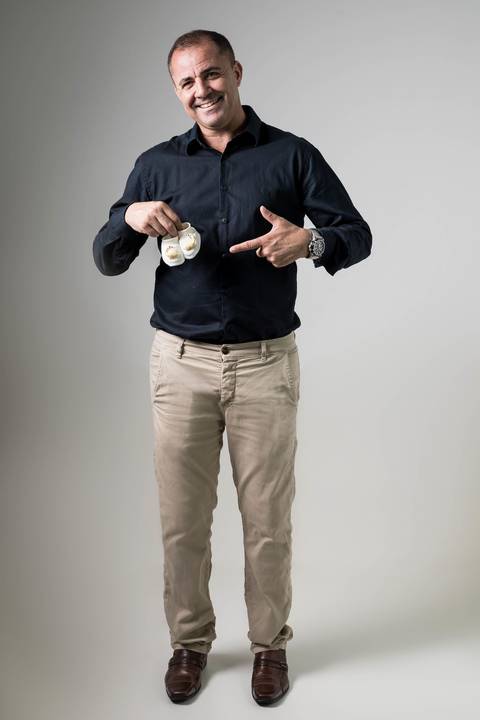 homem segurando sapatinhos de bebe'