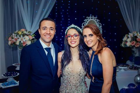 foto em familia em uma festa de 15 anos toda decorada de azul com baloes azuis e cortina branca e espelho no fundo com um tecido azul escuro com pisca pisca azul'