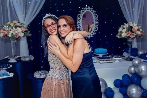 foto em familia em uma festa de 15 anos toda decorada de azul com baloes azuis e cortina branca e espelho no fundo com um tecido azul escuro com pisca pisca azul'