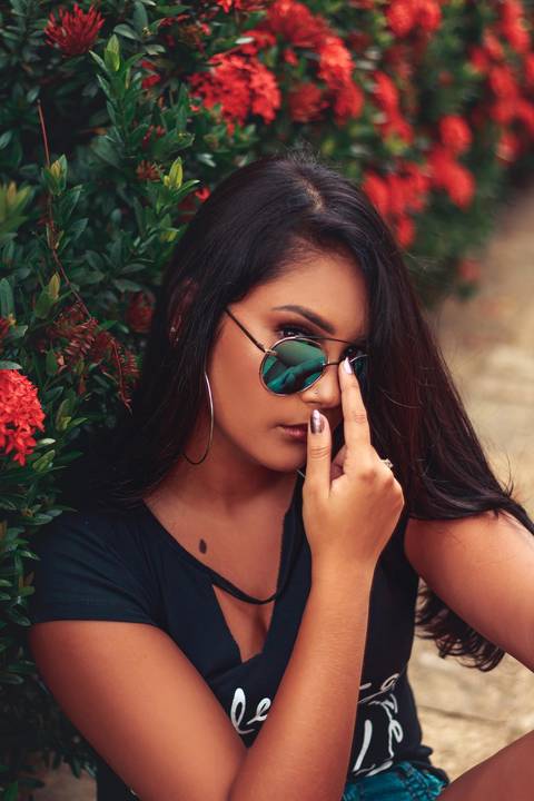 debutante sentada segurando o óculos de sol '