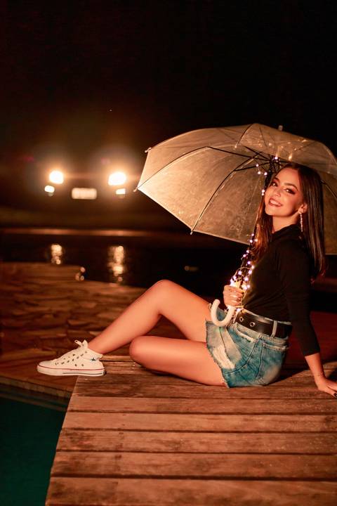 debutante segurando um guarda-chuva em frente a piscina'