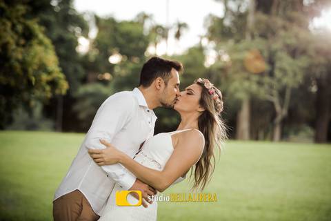 Casal em sessão pre-wedding em Piracicaba SP, em um beijo super apaixonado, noiva com vestido branco tiara de flores, noivo com camisa branca calça caqui, em um grande gramado.'