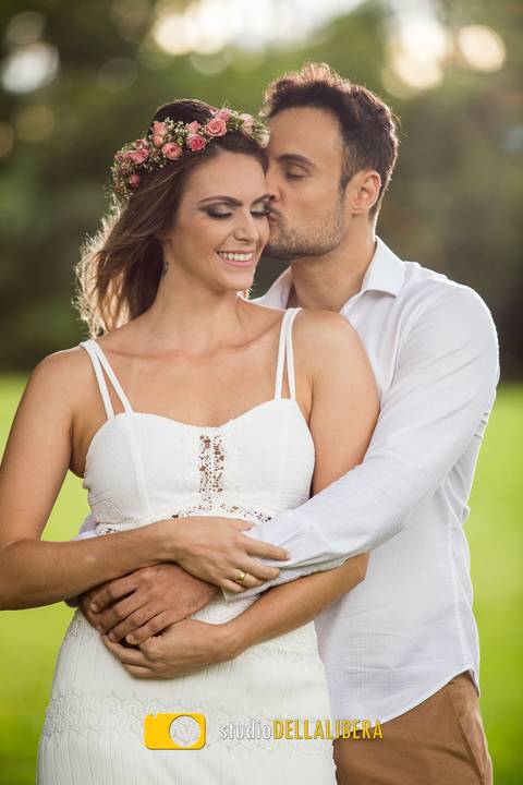 Noivos em um gramado, com arvores ao fundo, gramado verde '