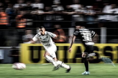 Zagueiro santista Alex em ação no clássico contra o Corinthians na Vila Belmiro. Técnica aplicada de panning.'