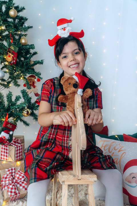 Ensaio de Natal em Família em Piraquara e Curitiba Paraná. Menina no cenário natalino com enfeites, brinquedos e arvore de natal.'