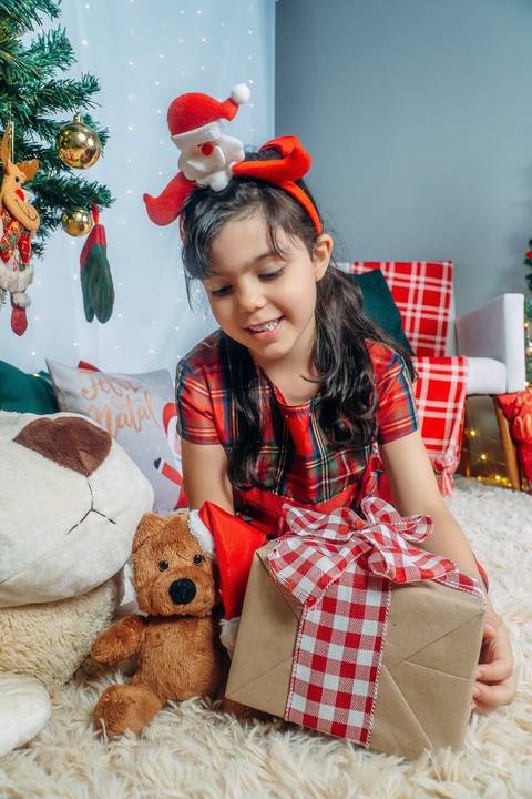 Ensaio de Natal em Família em Piraquara e Curitiba Paraná. Menina no cenário natalino com enfeites e arvore de natal.'