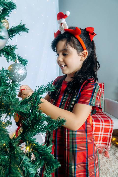 Ensaio de Natal em Família em Piraquara e Curitiba Paraná. Menina no cenário natalino com enfeites e arvore de natal.'