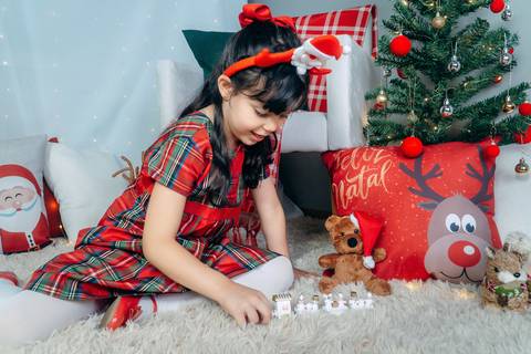 Ensaio de Natal em Família em Piraquara e Curitiba Paraná. Menina no cenário natalino com enfeites e arvore de natal.'