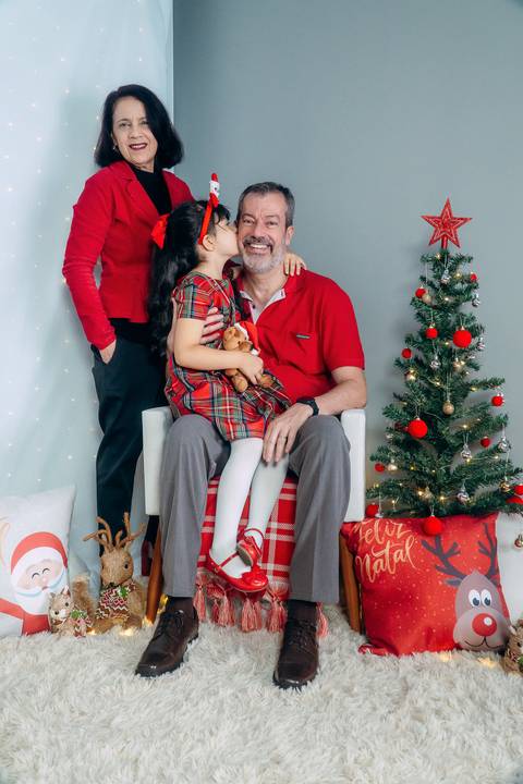 Ensaio de Natal em Família em Piraquara e Curitiba Paraná. Menina e seus avós no cenário natalino com enfeites e arvore de natal.'