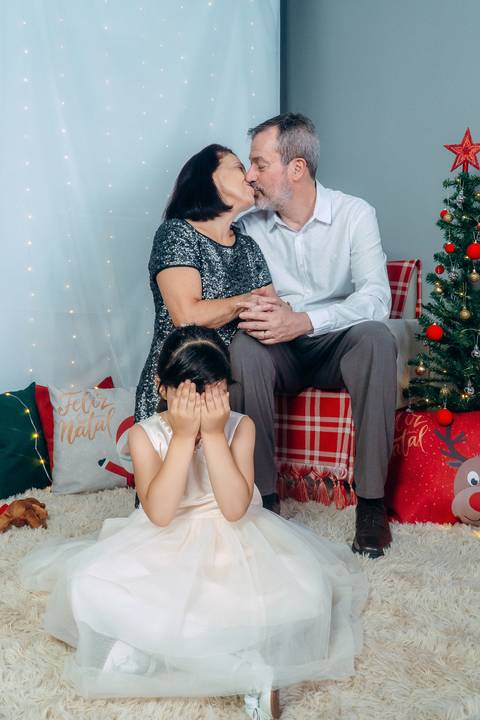 Ensaio de Natal em Família em Piraquara e Curitiba Paraná. Menina com seus avós no cenário natalino com enfeites e arvore de natal.'