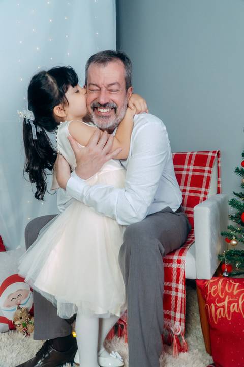 Ensaio de Natal em Família em Piraquara e Curitiba Paraná. Menina com seu avô no cenário natalino com enfeites e arvore de natal.'