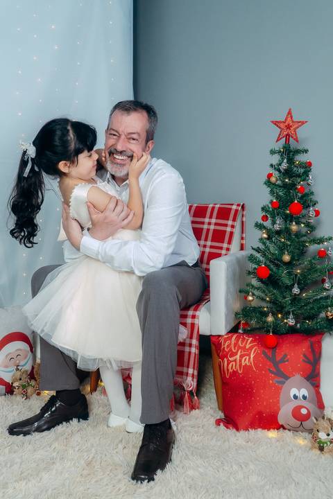 Ensaio de Natal em Família em Piraquara e Curitiba Paraná. Menina com seu avô no cenário natalino com enfeites e arvore de natal.'