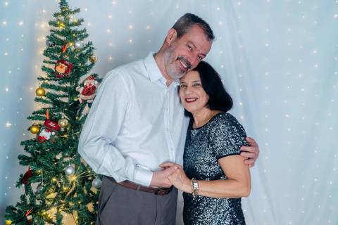 Ensaio de Natal em Família em Piraquara e Curitiba Paraná. Casal no cenário natalino com enfeites e arvore de natal.'