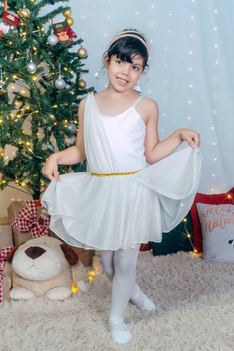 Ensaio de Natal em Família em Piraquara e Curitiba Paraná. Menia de vestido no cenário natalino com enfeites e arvore de natal.'