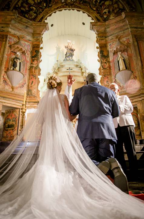fotografia da cerimônia dos noivos Camila e Roberto na Igreja do Rosário com os noivos Camila e Roberto em Ouro Preto Minas Gerais padre abençoando o casal'
