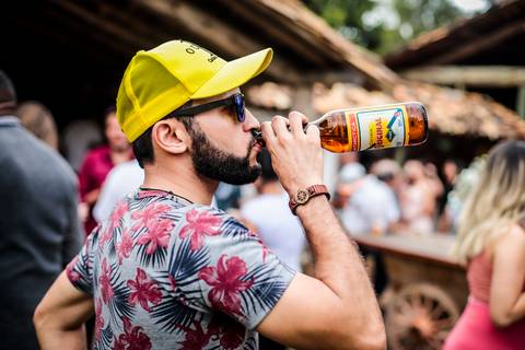 noivos mélani e pedro durante celebração de casamento com o recepção do casamento de mélani e pedro na fazenda engenho em piracema minas gerais , irmão da noiva bebendo cerveja no bico
'