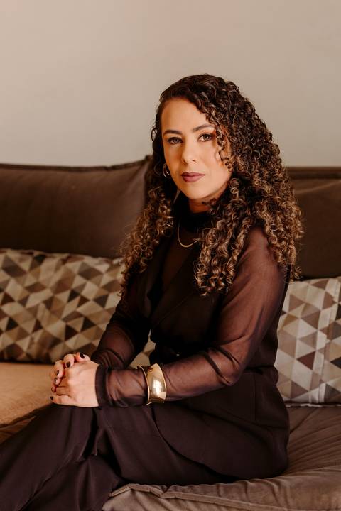 ensaio em casa fotos corporativas bom despacho renata bridges blazer marrom blusa branca cabelo cacheado make dia xícara branca computador quarto notebook look preto'