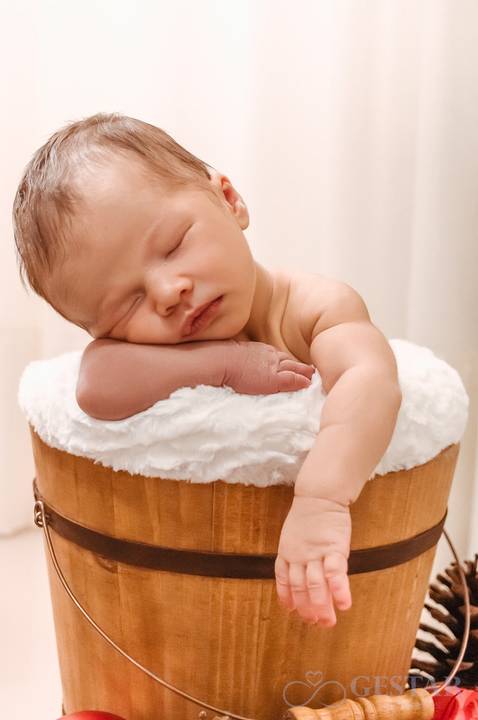 Bebê com 12 dias de vida dentro de baldinho de madeira
'