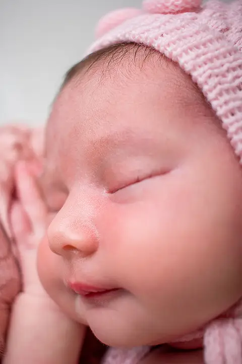 Cílios em destaque para o rosto da bebê, mostrando o nariz e ao fundo a mão. Foto pela fotógrafa Carol Zimmermann'