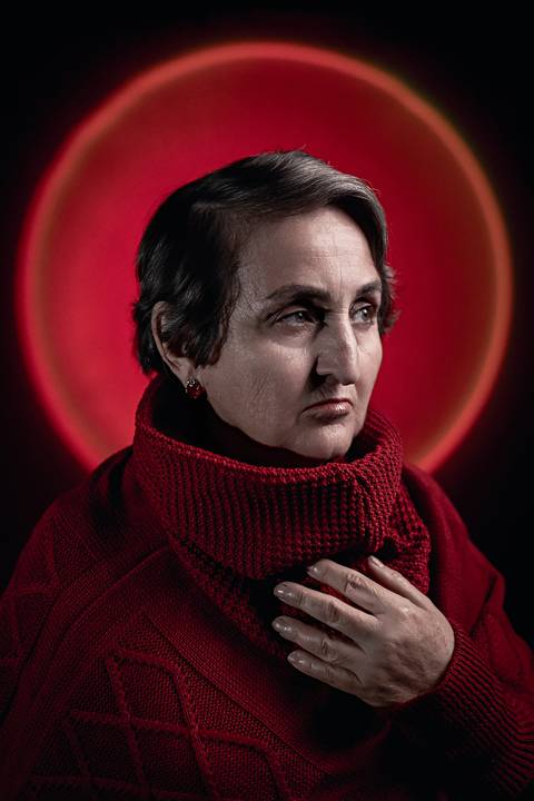 Imagem de mulher na faixa dos 50 anos olhando para o lado usando uma blusa de frio de gola alta.'