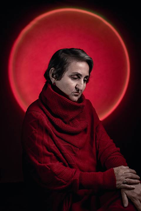 Imagem de mulher na faixa dos 50 anos com um olhar triste usando uma blusa de frio de gola alta.'