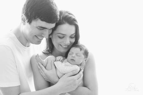 foto preto e branco ensaio de recem nascido newborn família que acabou de se formar e pais sorrindo olhando para o bebe ensaio newborn em brasilia'