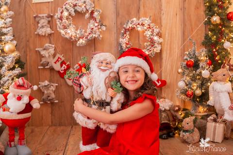 menina de gorro de natal abraçando papai noel'