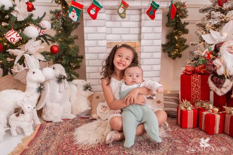 irma abraçando irmao bebe no cenario de natal'