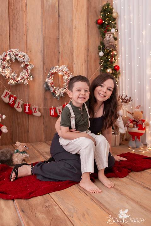 filho no colo da mãe no cenário de natal'