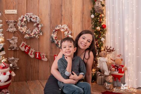 filho no colo da mãe no cenario de madeira de natal'