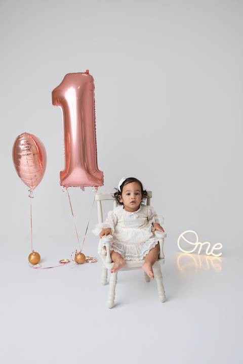 Celebração do primeiro ano de vida da pequena Maitê em Brasília. Registro afetivo da infância com balões em tons de rosé gold e cenário minimalista em destaque no DF.'