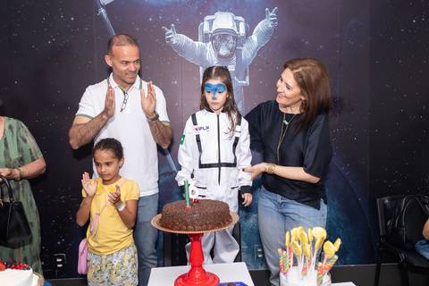 Retrato de família e laços de afeto na celebração de 6 anos da Anna. O carinho e a união dos pais e convidados durante o momento dos parabéns.'