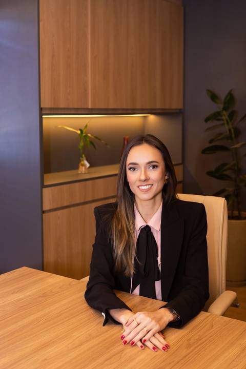 Retrato profissional de advocacia. Advogada Maíra em foto corporativa de estúdio no escritório, transmitindo autoridade e segurança para o perfil do LinkedIn e site.'
