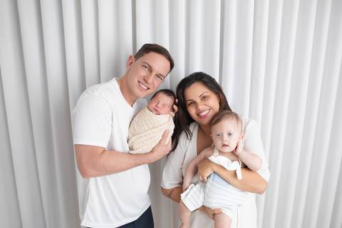 Retrato de família com recém-nascido. O casal Andrea e Marcos celebrando a chegada do bebê Rafael ao lado do filho Lucas em um momento cheio de afeto.'