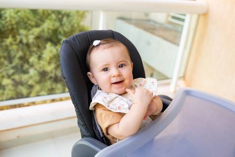 Introdução alimentar e descobertas sensoriais na infância. A bebê Cecília aos 8 meses experimentando manga em momento espontâneo e lúdico com frutas.'